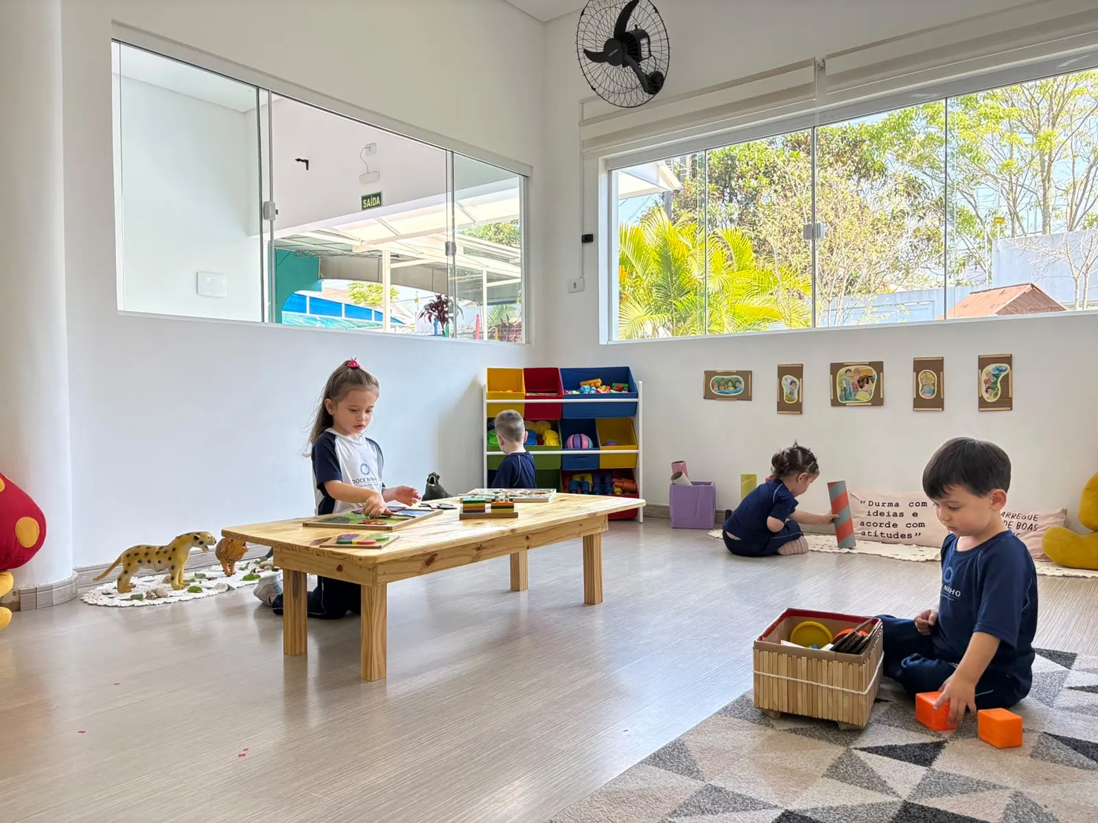 Crianças brincando com jogos e materiais em diferentes cantos da sala de aula