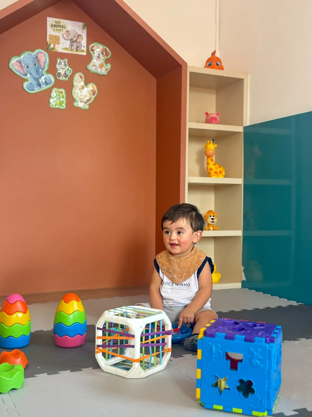 Bebê explorando brinquedos de encaixe no tapete do berçário da Doce Ninho