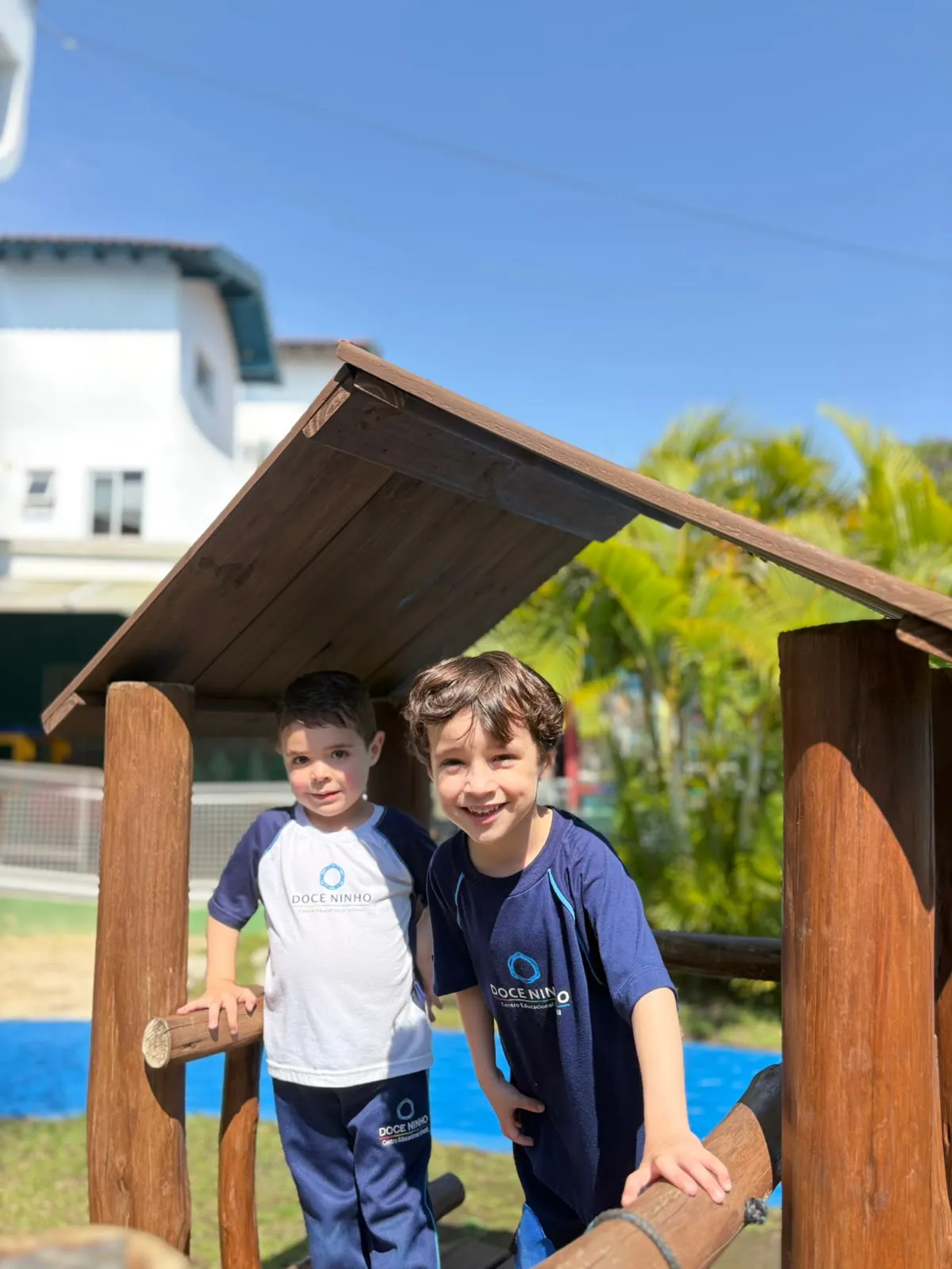 Duas crianças brincando na casinha de madeira da área externa da escola