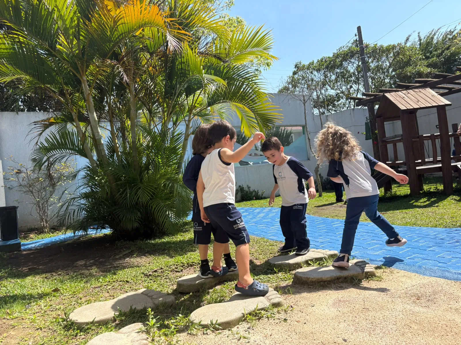 Crianças brincando em um percurso de pedras no jardim da Doce Ninho
